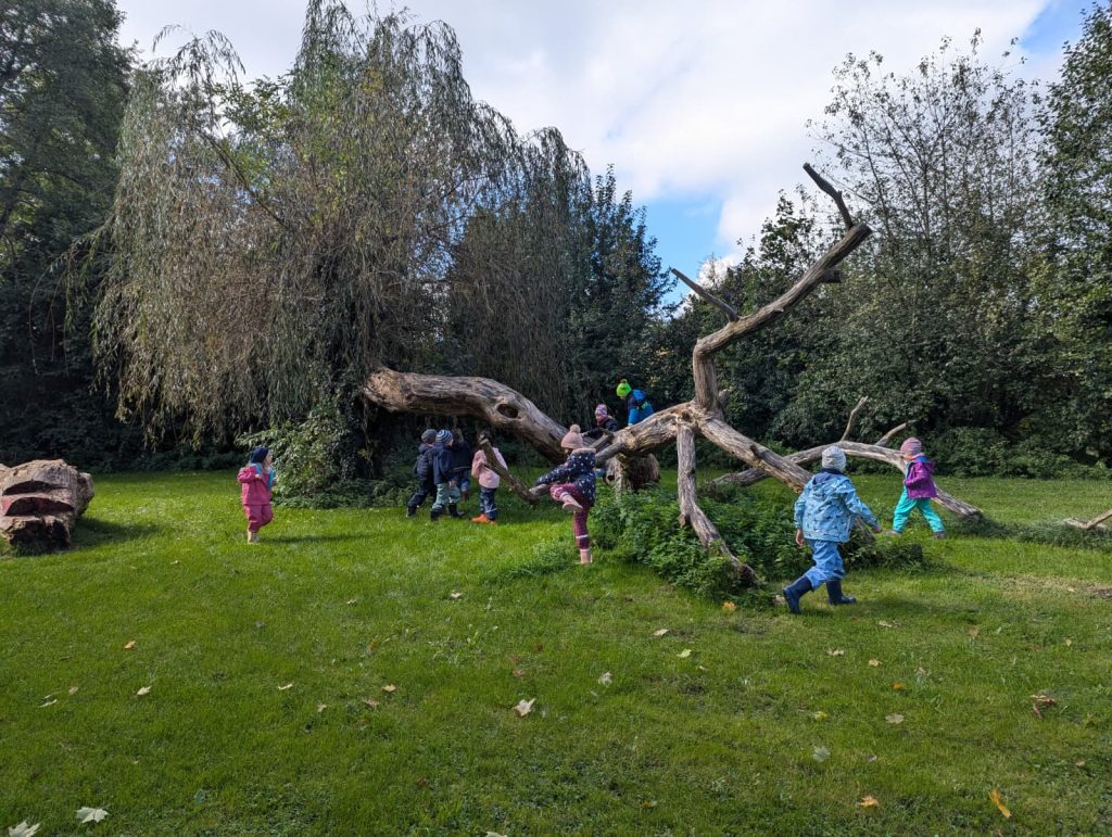 Kinder spielen an Totholzstamm an der Ilm